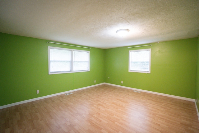 unfurnished room with a textured ceiling and light hardwood / wood-style floors