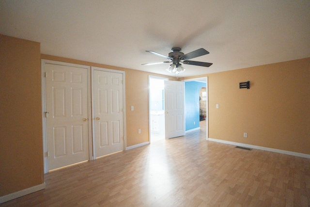 unfurnished bedroom featuring two closets, ceiling fan, and hardwood / wood-style floors