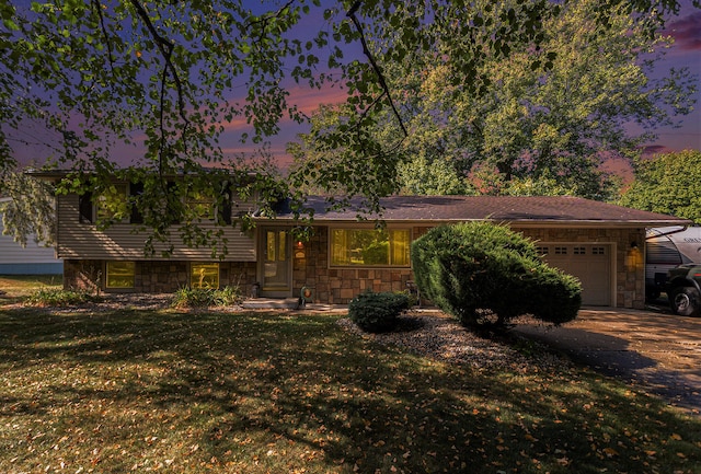 tri-level home featuring a garage and a lawn