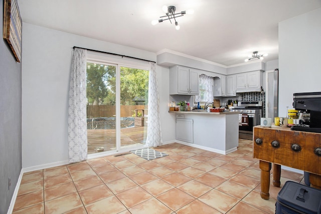 kitchen with white cabinets, light tile patterned floors, kitchen peninsula, stainless steel range, and crown molding