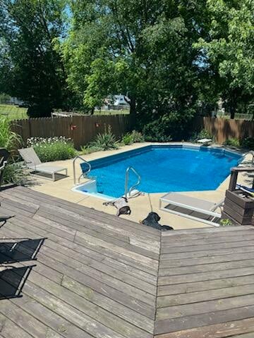 view of pool with a diving board and a deck