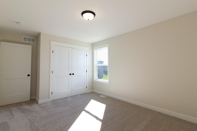 unfurnished bedroom with light colored carpet and a closet