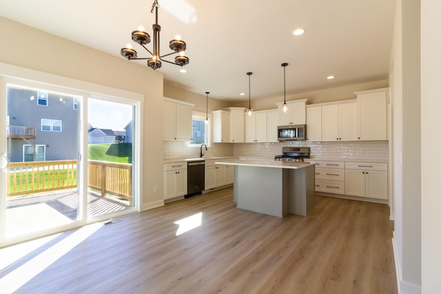 kitchen featuring hanging light fixtures, a kitchen island, white cabinetry, stainless steel appliances, and light wood-type flooring