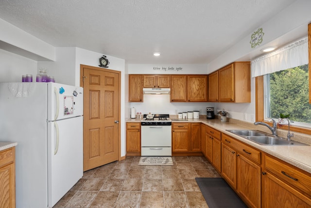 kitchen featuring white appliances, a textured ceiling, and sink