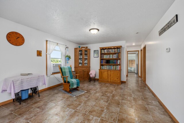 living area with cooling unit, a textured ceiling, and tile patterned flooring