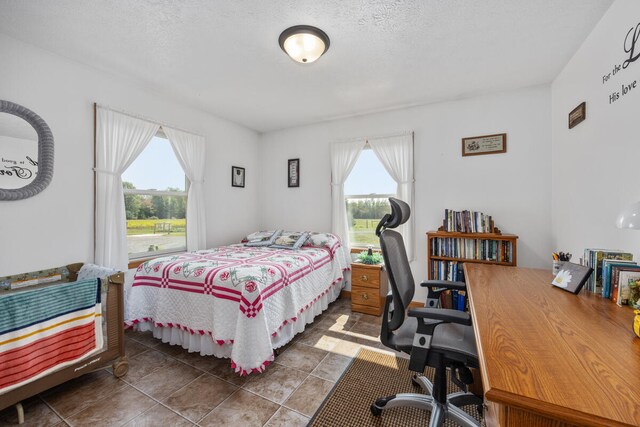 bedroom featuring a textured ceiling, dark tile patterned flooring, and multiple windows