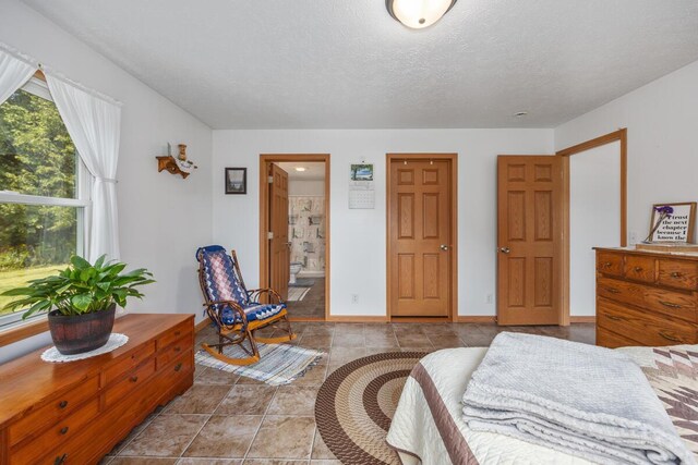 bedroom featuring a textured ceiling, ensuite bath, and light tile patterned floors