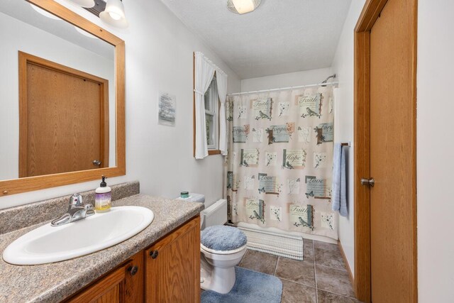 full bathroom with vanity, a textured ceiling, tile patterned flooring, shower / tub combo with curtain, and toilet