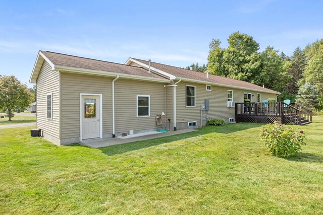 back of house featuring a wooden deck, a patio, and a lawn