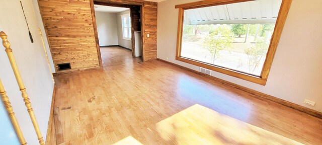 empty room with light wood-type flooring and wooden walls