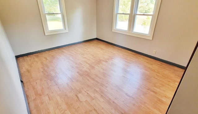 empty room with light hardwood / wood-style floors and a healthy amount of sunlight