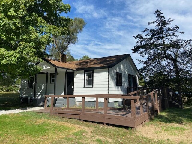 view of front of home with a deck and a front lawn