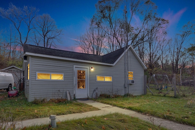 ranch-style home featuring cooling unit, a yard, and an outbuilding