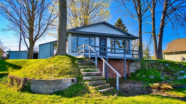 view of front facade featuring a sunroom, brick siding, a wooden deck, and stairs