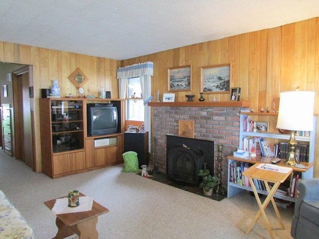 living room with carpet, wooden walls, and a brick fireplace