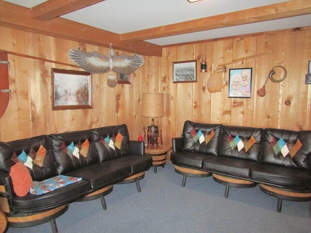 living room with carpet, wooden walls, and beam ceiling