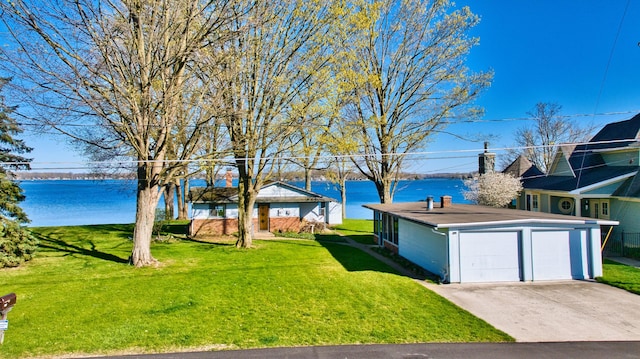 view of yard featuring a garage, concrete driveway, and a water view