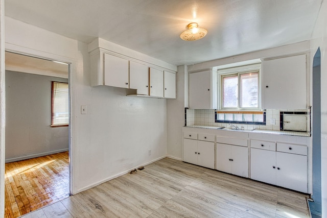 kitchen featuring sink, white cabinetry, tile counters, light wood-type flooring, and decorative backsplash