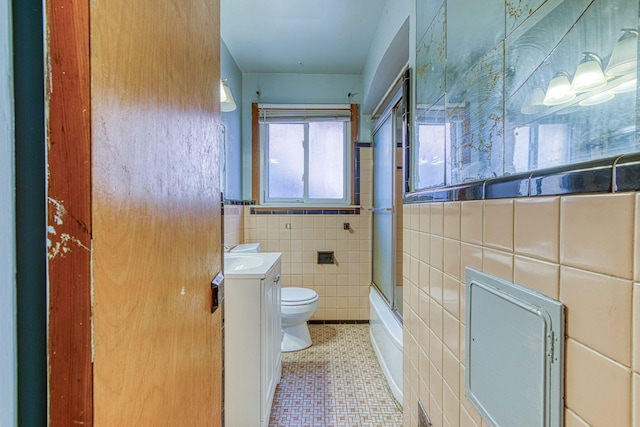 full bathroom featuring tile walls, vanity, tile patterned flooring, shower / bath combination with glass door, and toilet