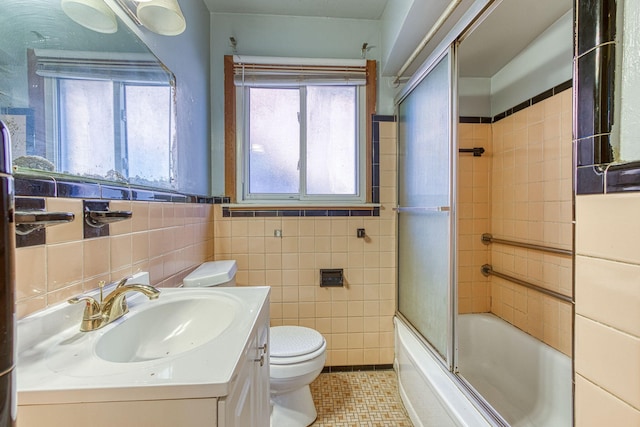 full bathroom with tile walls, shower / bath combination with glass door, toilet, and vanity