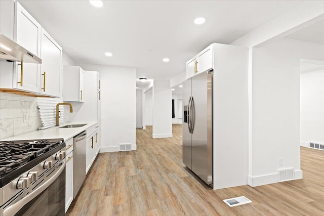 kitchen featuring stainless steel appliances, light wood-type flooring, sink, and white cabinetry