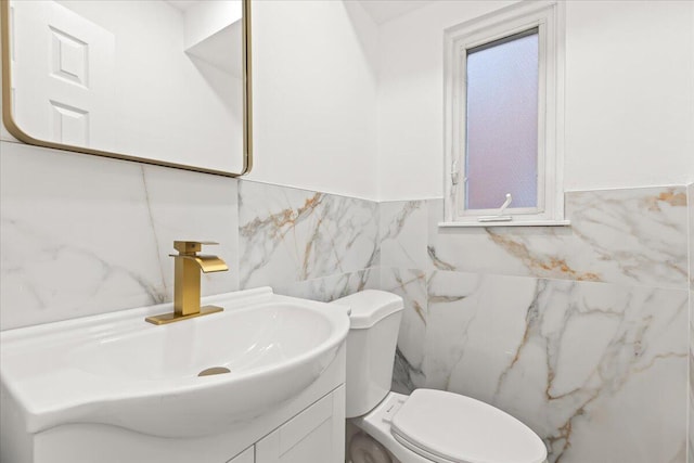 bathroom with tile walls, vanity, and toilet