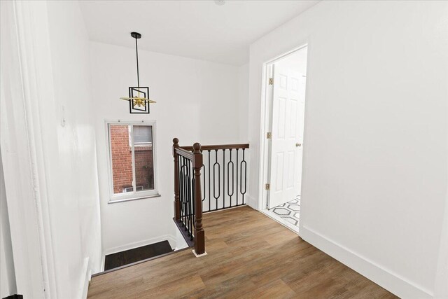 hall featuring wood-type flooring and a notable chandelier