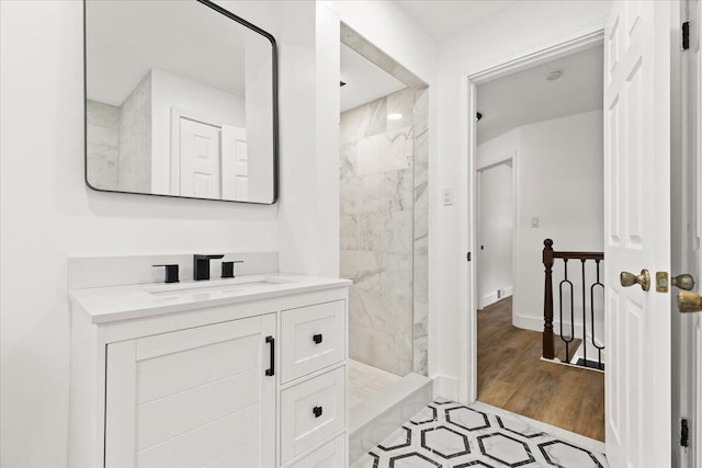 bathroom with wood-type flooring, vanity, and tiled shower