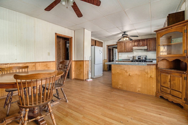 kitchen featuring light wood-type flooring, stainless steel stove, kitchen peninsula, white fridge, and ceiling fan