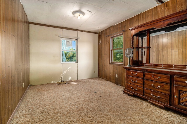 unfurnished bedroom with wooden walls, carpet floors, and crown molding