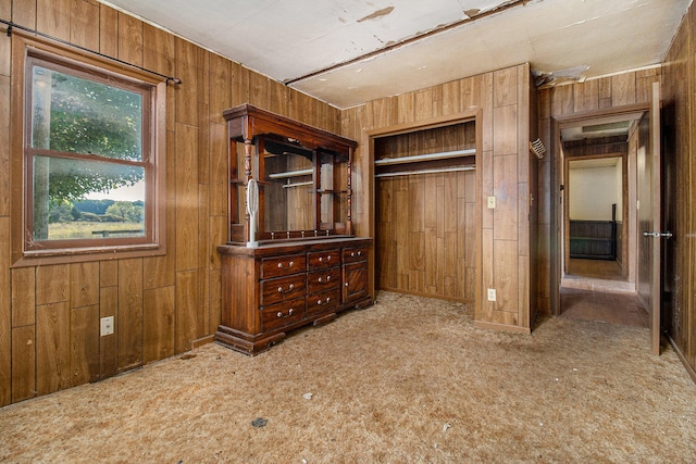 unfurnished bedroom with a closet, wooden walls, and carpet flooring