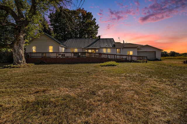 back house at dusk featuring a wooden deck and a yard