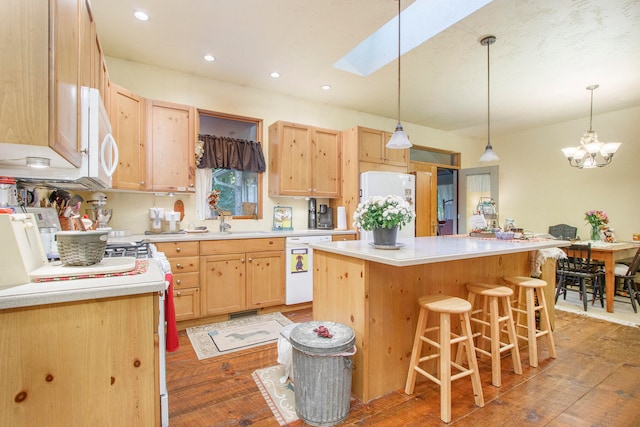 kitchen with light brown cabinetry, white appliances, hardwood / wood-style flooring, and a kitchen island