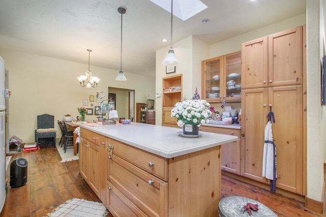 kitchen featuring a skylight, a kitchen island, hanging light fixtures, and dark wood-type flooring