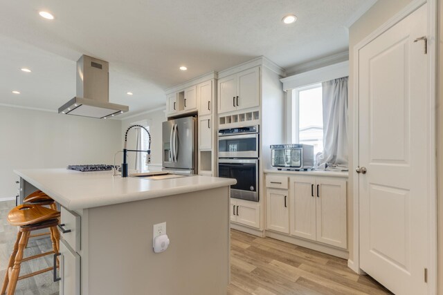 kitchen with white cabinetry, stainless steel appliances, light hardwood / wood-style flooring, range hood, and a kitchen island with sink