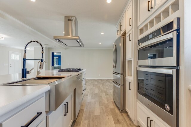 kitchen with island range hood, white cabinetry, light hardwood / wood-style flooring, and stainless steel appliances