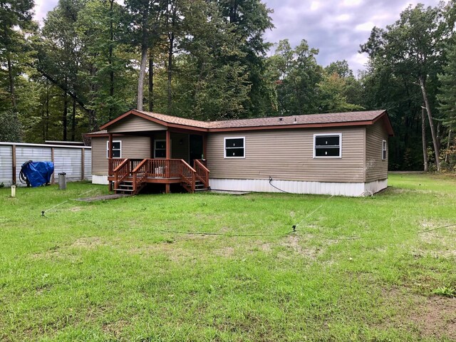 rear view of house featuring a yard and a wooden deck