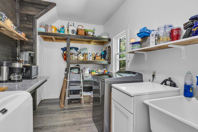 clothes washing area with separate washer and dryer, sink, and hardwood / wood-style floors