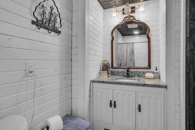 bathroom featuring walk in shower, vanity, wood walls, and toilet