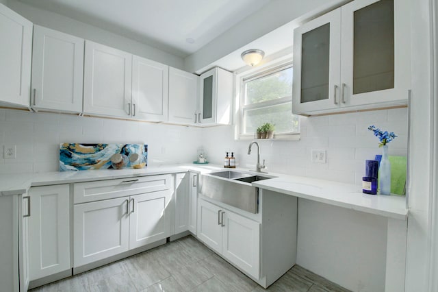 kitchen with white cabinetry, light stone countertops, sink, and tasteful backsplash