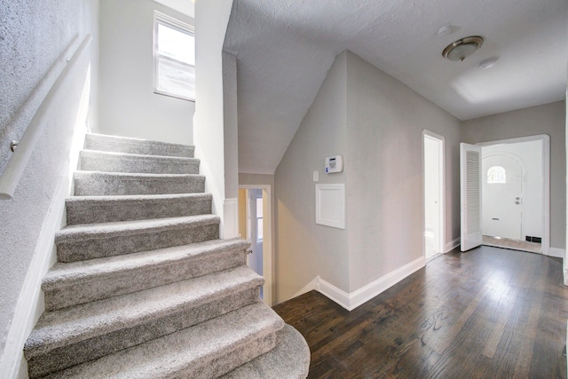 entrance foyer featuring a textured ceiling, lofted ceiling, and dark hardwood / wood-style flooring