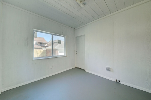 empty room featuring concrete floors, wooden ceiling, and crown molding