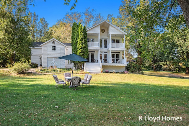 rear view of house with a balcony, a yard, and an outdoor fire pit