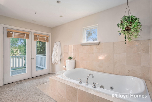 bathroom featuring french doors and a relaxing tiled tub