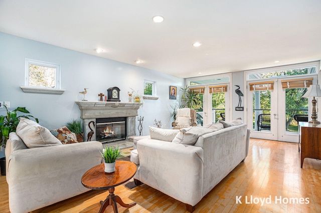 living room featuring light hardwood / wood-style flooring, a wealth of natural light, a high end fireplace, and french doors