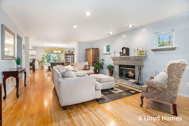 living room featuring light hardwood / wood-style flooring, a premium fireplace, and a chandelier