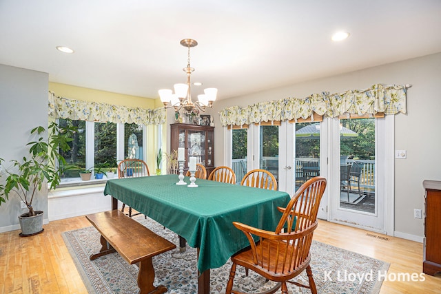 dining space with light hardwood / wood-style floors, an inviting chandelier, and french doors