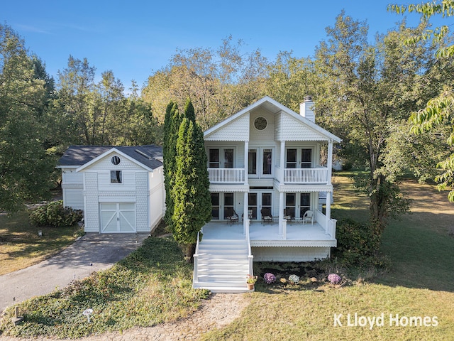 greek revival house featuring a balcony, a garage, a front yard, and covered porch