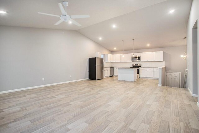 kitchen with pendant lighting, white cabinets, lofted ceiling, light hardwood / wood-style flooring, and stainless steel appliances