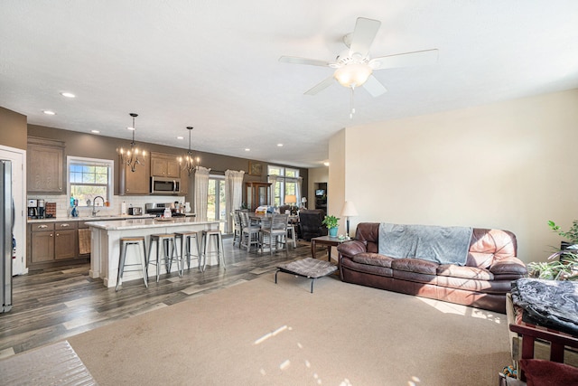 living room with ceiling fan with notable chandelier, dark hardwood / wood-style floors, and sink